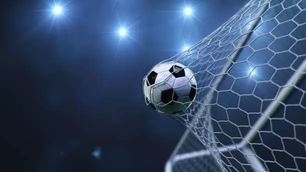 Photo of Soccer ball flew into the goal. Soccer ball bends the net, against the background of flashes of light. Soccer ball in goal net on blue background. A moment of delight. 3D illustration