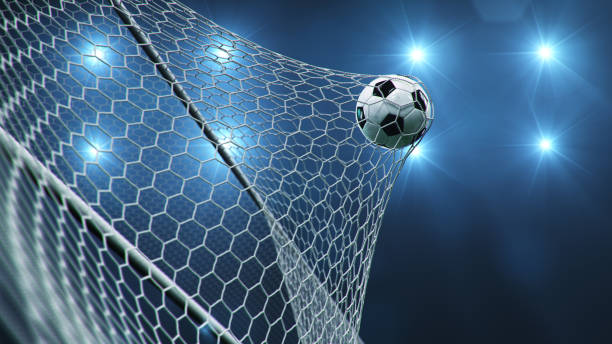 サッカーボールがゴールに飛び込んだ。サッカーボールは、光のフラッシュの背景に対して、ネットを曲げ、ネットを曲げます。青い背景にゴールネットでサッカーボール。喜びの瞬間。3d � - サッカー ストックフォトと画像