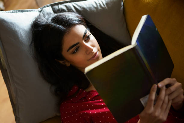 istock Persian woman at home reading on a couch 1197593668