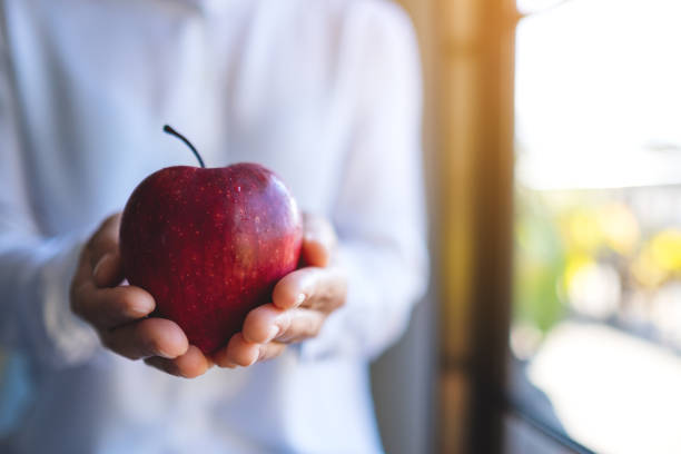 istock a woman holding a red apple 1197605682