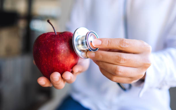 istock a doctor using stethoscope to examine a red apple 1197605719