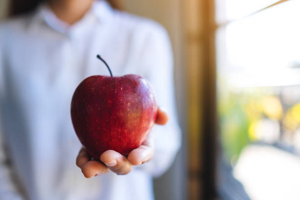 istock a woman holding a red apple 1197605733