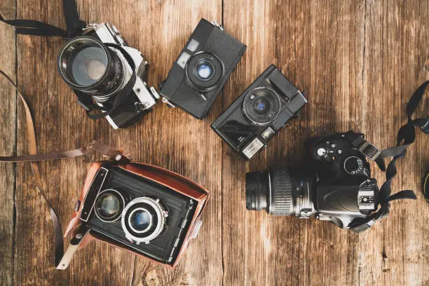 Photo of The evolution of the photo cameras on a wooden backraound. Camera technology concept.