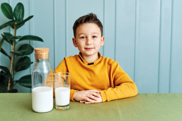 istock 6-7 years old cute child drinking milk on table. He knows that he needs to drink milk for healthy bones. He loves milk. 1197609183