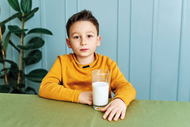 istock 6-7 years old cute child drinking milk on table. He knows that he needs to drink milk for healthy bones. He loves milk. 1197609187