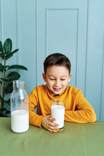 istock 6-7 years old cute child drinking milk on table. He knows that he needs to drink milk for healthy bones. He loves milk. 1197609237