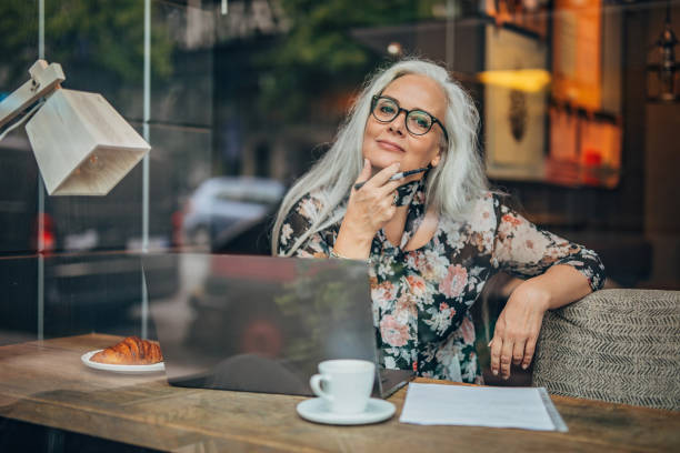 mulher de negócio velha que senta-se no café sozinho - só uma mulher madura - fotografias e filmes do acervo