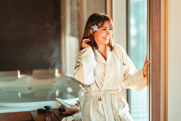 beautiful woman is looking out from window while waiting for massage at spa center.