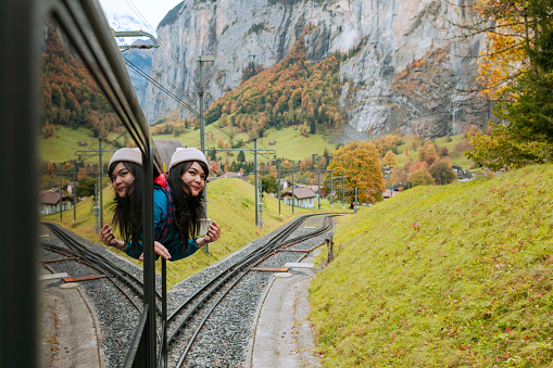 happy smiling woman looks out from windows traveling by train on most picturesque train road in Swiss