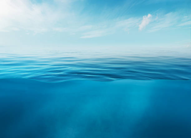 superficie blu del mare o dell'oceano e sott'acqua con cielo soleggiato e nuvoloso - horizon over water environment vacations nature foto e immagini stock