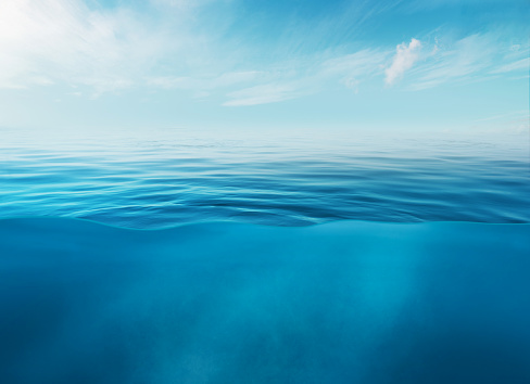 Blue sea or ocean water surface and underwater with sunny and cloudy sky.
