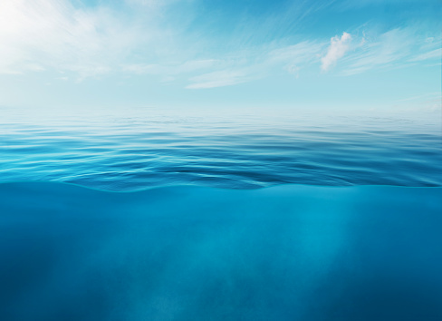 Blue sea or ocean water surface and underwater with sunny and cloudy sky