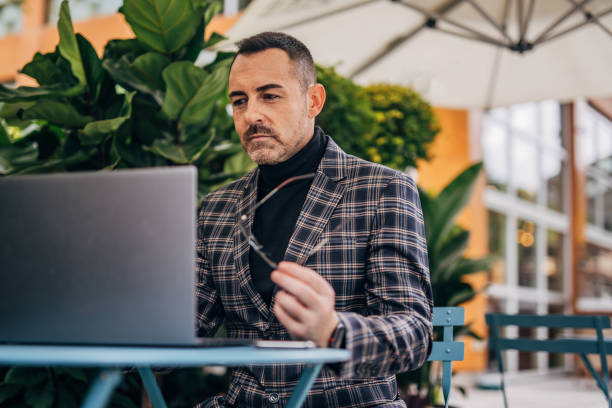 istock Businessman using laptop in sidewalk cafe 1197639013