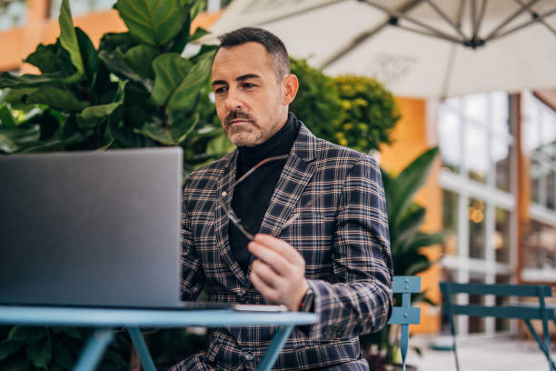 istock Businessman using laptop in sidewalk cafe 1197639094