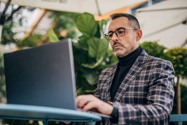 istock Businessman using laptop in sidewalk cafe 1197639112