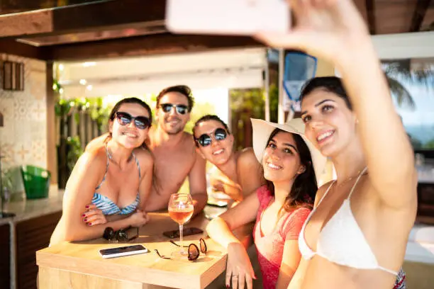 Photo of Group of friends / family on vacation taking a selfie using smart phone at beach house