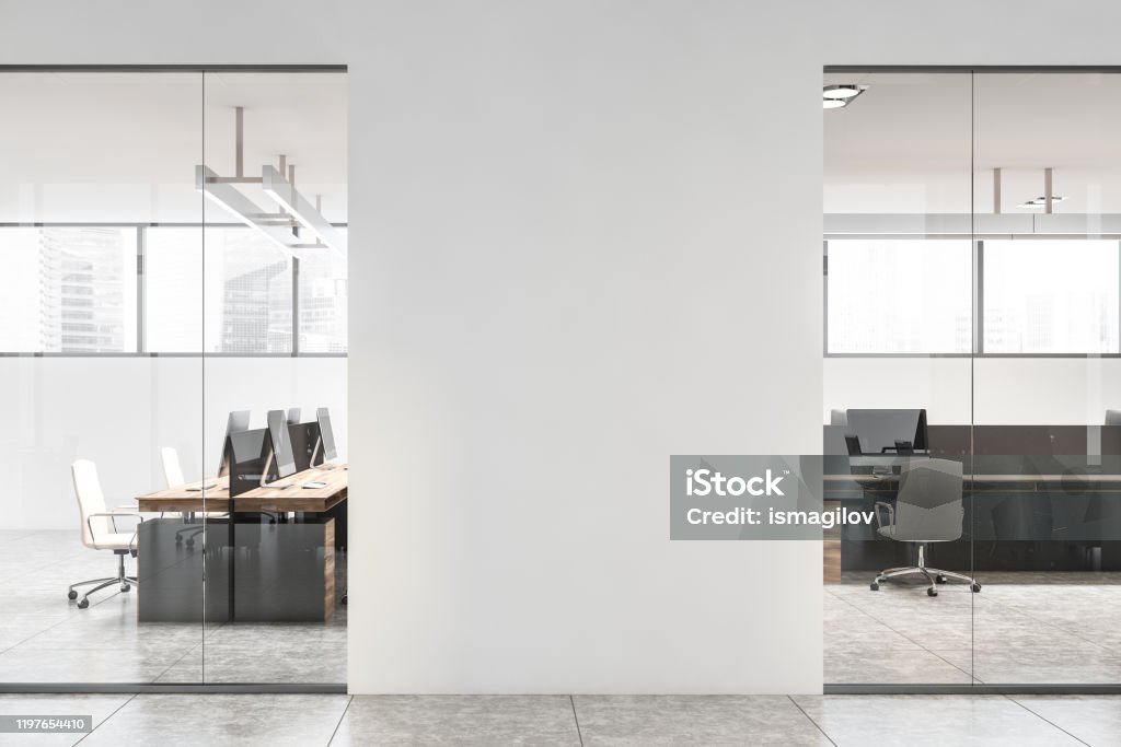 White office interior with mock up wall Interior of stylish office with white walls, concrete floor, wooden computer tables and mock up wall in the hall. 3d rendering Office Stock Photo