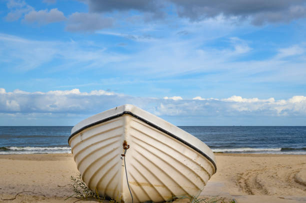 barca solitaria sdraiata sulla spiaggia di sabbia sulla costa dell'isola usedom, germania. - rowboat nautical vessel usedom sand foto e immagini stock
