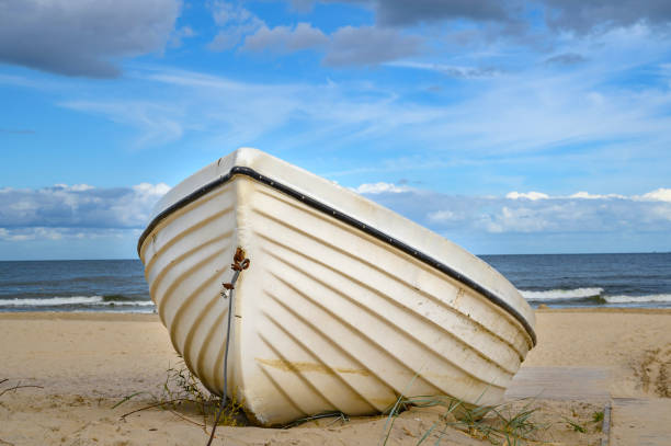 barca solitaria sdraiata sulla spiaggia di sabbia sulla costa dell'isola usedom, germania. - rowboat nautical vessel usedom sand foto e immagini stock