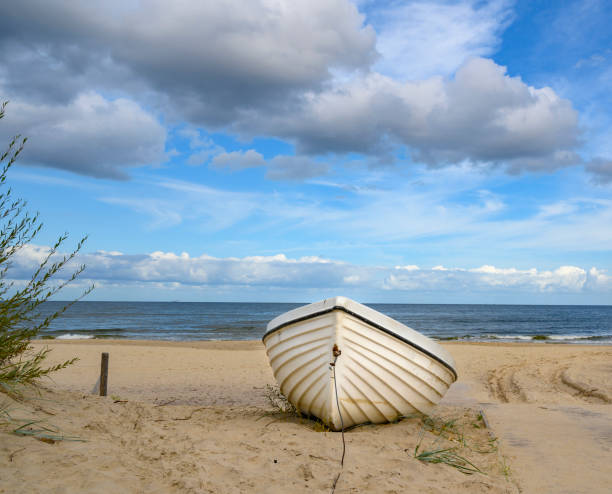 barca solitaria sdraiata sulla spiaggia di sabbia sulla costa dell'isola usedom, germania. - rowboat nautical vessel usedom sand foto e immagini stock