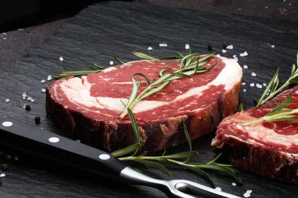 istock Raw fresh meat Ribeye Steak, seasoning and meat fork on rustic background 1197659225