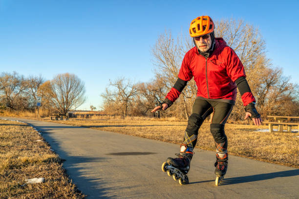 Senior athletic male in helmet and protective gear is inline skating on a paved bike trail - Boyd Lake Trail in northern Colorado in winter scenery