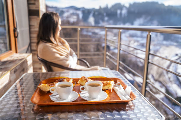 冬の朝、スキーリゾートでコーヒーと朝食を飲みながら目を覚ます。朝の日差しの前で熟考。ロマンチックな休暇が始まります。 - winter women zen like photography ストックフォトと画像