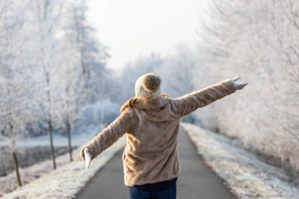 Happy woman enjoying fresh air during walk in winter nature Fashion model wearing fur coat and knitted hat with arms outstretched outdoors. Cold weather with frozen trees winter stock pictures, royalty-free photos & images