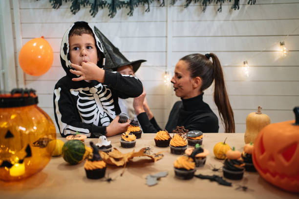 istock Cute children eating muffins on Halloween while celebrating with mother 1197664732