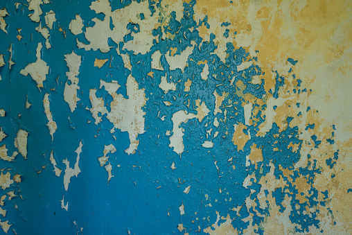 Colorful cement stone wall. Cracked wall with old layers of paint in abandoned house