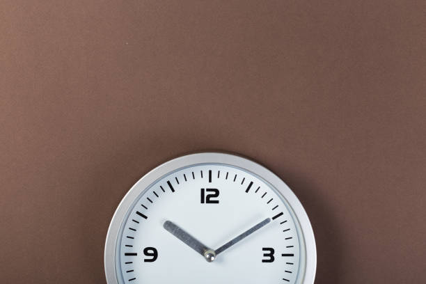 istock minimalistic white wall clock with light metal on a brown background. time concept. 1197669520