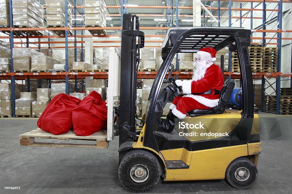 Babbo Natale con un carrello elevatore a forca operatore al lavoro in magazzino - Foto stock royalty-free di Natale