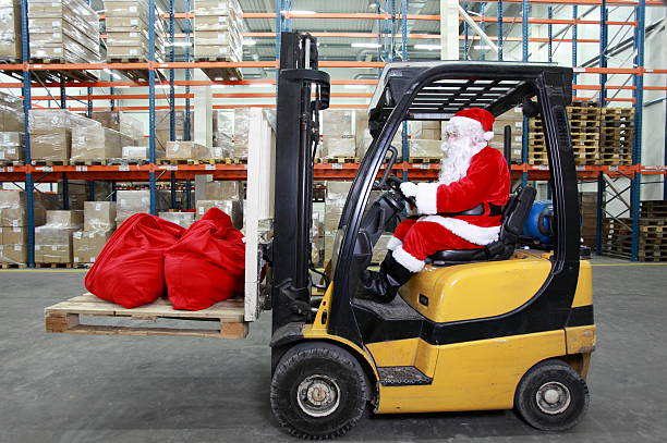 Santa Claus as a forklift operator at work in warehouse stock photo