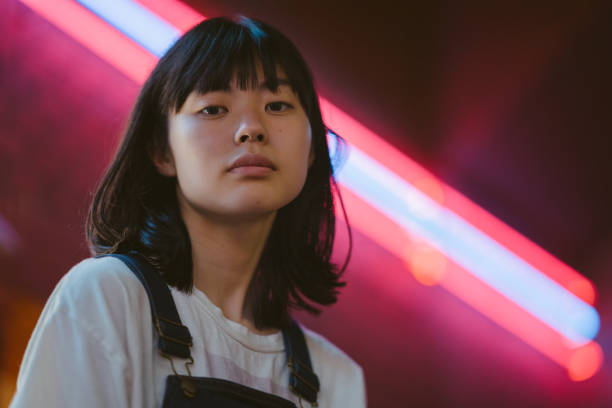 Portrait of young woman lit up by neon colored lights at night A portrait of a young woman lit up by neon colored lights at night low angle street japan stock pictures, royalty-free photos & images
