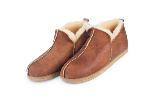 Studio shot of a pair of mens sheepskin slippers cut out against a white background