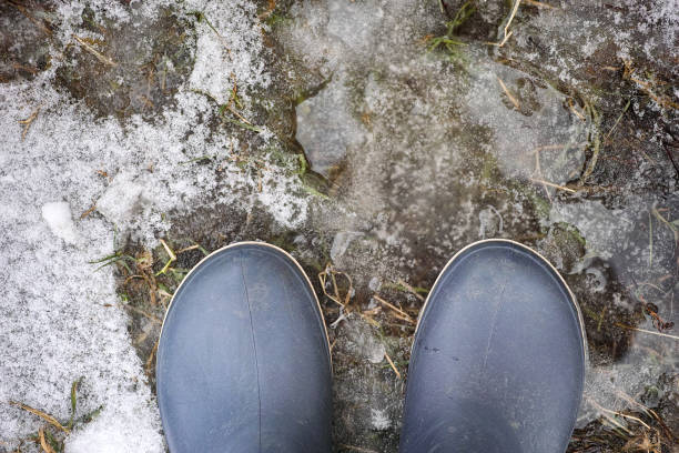 Person in boots standing on on melted snow. Close up.