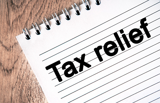 Text - tax relief on a notebook sheet. Wooden table