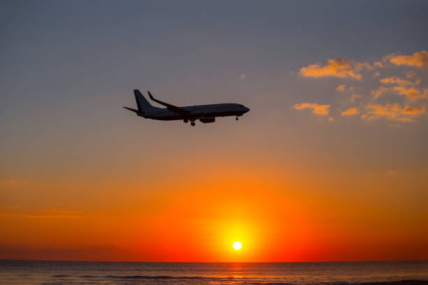 istock airplane silhouette fly over the sunset background 1197679840