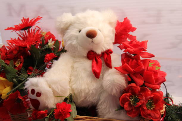 istock white teddy bear with flowers 1197682171