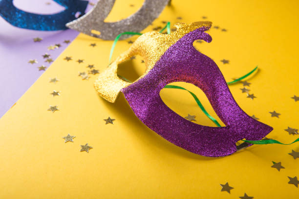 A festive, colorful group of mardi gras or carnivale mask on a yellow purple background. Venetian masks. A festive, colorful group of mardi gras or carnivale mask on a yellow purple background. Venetian masks. gawdy stock pictures, royalty-free photos & images