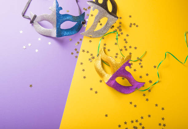 A festive, colorful group of mardi gras or carnivale mask on a yellow purple background. Venetian masks. A festive, colorful group of mardi gras or carnivale mask on a yellow purple background. Venetian masks. gawdy stock pictures, royalty-free photos & images