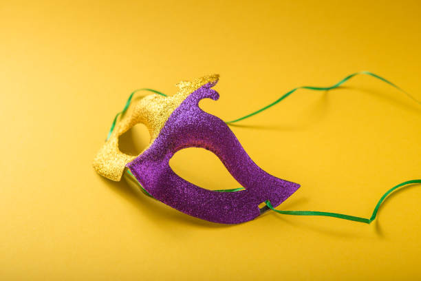 A festive, colorful group of mardi gras or carnivale mask on a yellow purple background. Venetian masks. A festive, colorful group of mardi gras or carnivale mask on a yellow purple background. Venetian masks. gawdy stock pictures, royalty-free photos & images