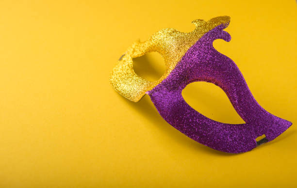 A festive, colorful group of mardi gras or carnivale mask on a yellow purple background. Venetian masks. A festive, colorful group of mardi gras or carnivale mask on a yellow purple background. Venetian masks. gawdy stock pictures, royalty-free photos & images