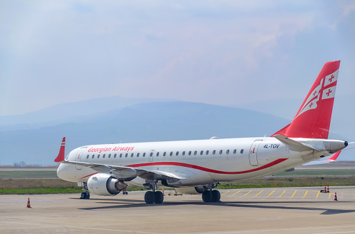 Georgian Airlines plane at the airport on a background of mountains. Georgia, Tbilisi, 2019-04-10