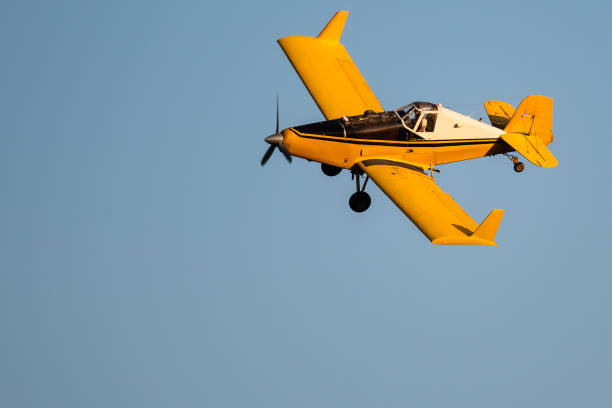 istock Yellow Crop Dusting Plane Flying in a Blue Sky 1197686953