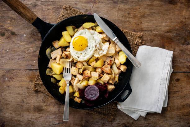 Traditional Danish food dish of “Biksemad” which translates as “mixed-food” it is a good way of using up left over food food. It usually consists of pieces of left over roast pork, or flæskesteg, boiled potatoes and fried white onions topped off with one or two fried eggs and served with pickles and or beetroot or red cabbage. Colour, horizontal, overhead view with some copy space.