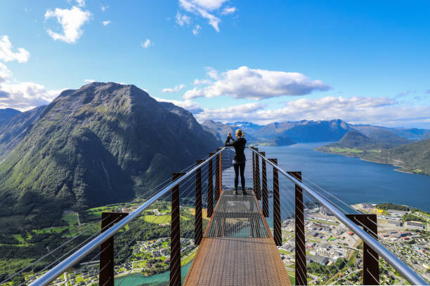 Woman on suspension platform taking mountaintop photo of Andalsnes Norway stock photo