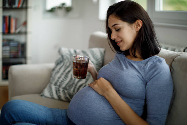 mujer embarazada relajándose en casa - infusión té bebida fotografías e imágenes de stock