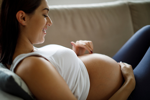 Pregnant woman playing with her belly at home