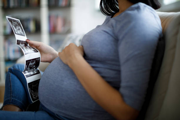 schwangere frau mit blick auf ultraschall-scan von baby - human pregnancy uterus abdomen man woman stock-fotos und bilder